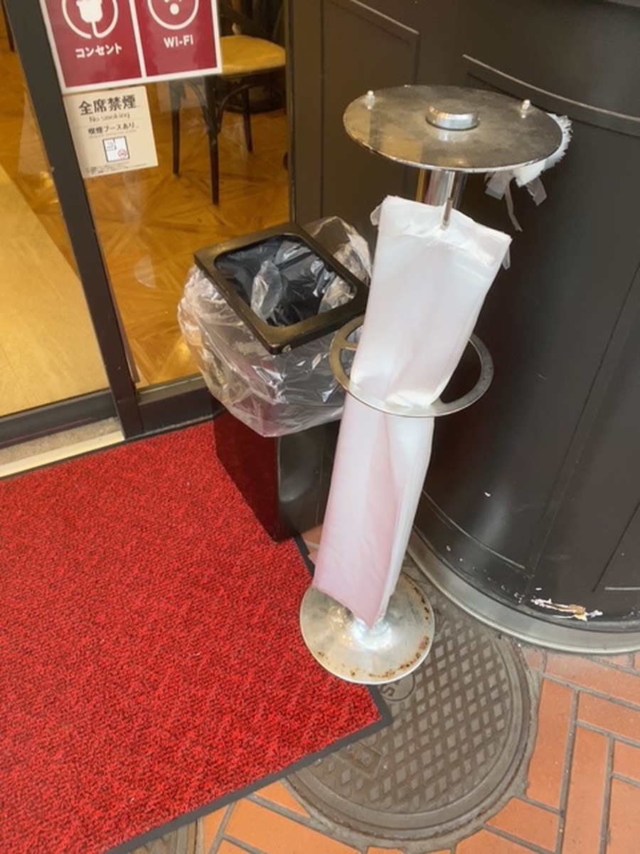 Long plastic umbrella sleeves provided for wet umbrellas at a building entrance in Japan.