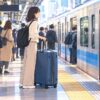 Traveler with a large suitcase at a busy urban train station in Tokyo.