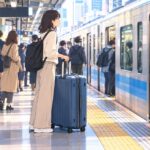 Traveler with a large suitcase at a busy urban train station in Tokyo.