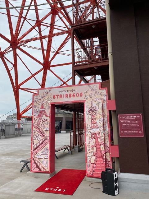 Entrance gate marking the start of Tokyo Tower's outdoor 'Stairs600' staircase route, with a red start mat on the ground.